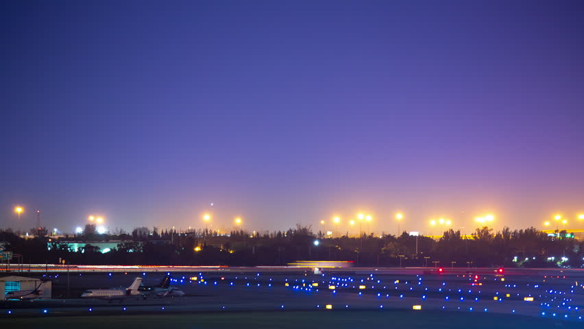 Vibrant Commercial Aviation Airport Airfield Action Timelapse at Night with Light Streaks from Jet Airliners Landing and Taking off in a Colorful Sky Royalty-Free Stock Footage #1010212652