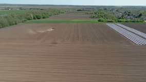 Aerial flight of field with tractor, slow motion video