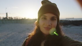 portrait of young lively woman student talking waving hand excited holding camera making video call sharing beautiful beach vacation slow motion
