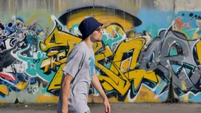 Young man is walking along the street with graffiti painting on the background and a spray in his hands - Powered by Shutterstock - Get 15% off with code: PIKWIZARD15