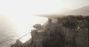 High key into the sun aerial drone footage orbit POI from Mediterranean Sea view to front wall of Mamure Castle ruins in Anamur, Turkey. 