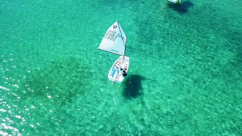 April 22 2018: Aerial drone bird's eye view video of small sail boats operated by children cruising in bay of Porto Rafti, Avlaki, Attica, Greece