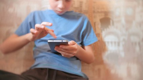 Seven-year-old boy browsing internet on his mobile phone with serious face.