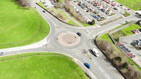 Panoramic bird's-eye aerial view of traffic navigating a small road roundabout in the UK.