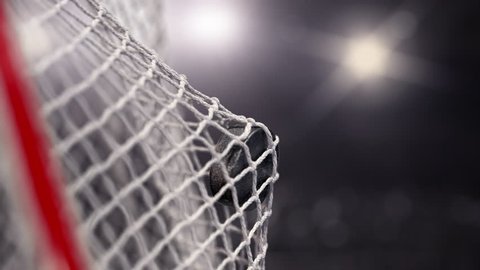 Hockey puck flies into the net on a lights stadium. The movement at the beginning is accelerated then slowly. Beautiful close-up (4k, 3840x2160, ultra high definition)