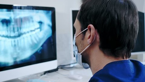 Man dentist looking at x-ray in private practice.: stockvideo