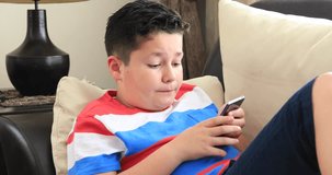 Portrait of a happy preteen boy sitting on sofa and using smartphone at home. Technology, internet communication and people concept, Smartphone addiction