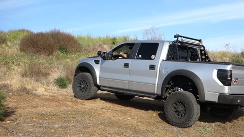 Valley Center, CA / USA - April 25, 2018: A customized 2011 Ford F-150 Raptor SVT pick-up truck drives on a dirt road in Southern California