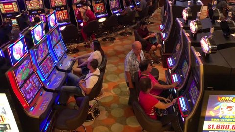 MACAU - SEP 2017: People play on slot machines at Grand Lisboa hotel. Macau is a resort city in Southern China with casinos and luxury hotels. Its gaming revenue has been the worlds largest since 2006