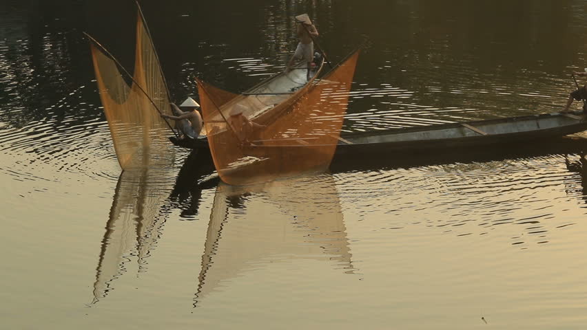 Vietnamese fishermen throw the big casting net into the river and then draw it back in Hue City, Vietnam