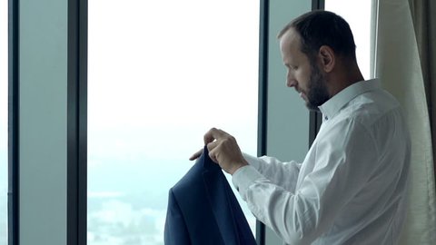 Young businessman putting on jacket and admire view at home 
