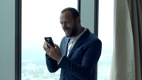 Happy, successful businessman getting good news on smartphone in office 
