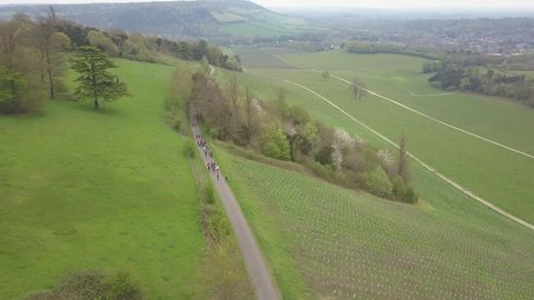 SURREY, UNITED, KINGDOM- APRIL, 2018: View of large group of hikers walking down a country lane towards Box Hill, a famous landmark and nature area close to Dorking in southern England