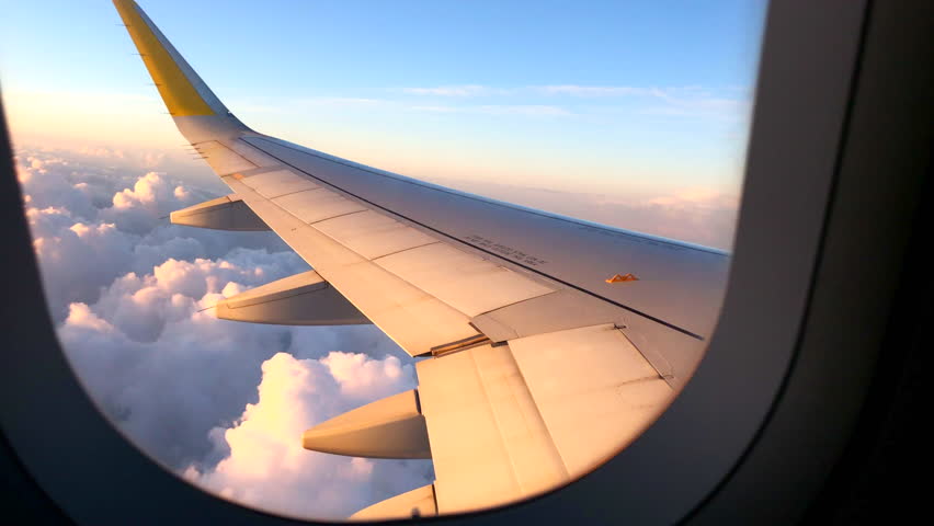 Airplane flight. Wing of an airplane flying above the clouds with sunset sky. View from the window of the plane. Airplane, Aircraft. Traveling by air. 4K UHD video Royalty-Free Stock Footage #1010280311