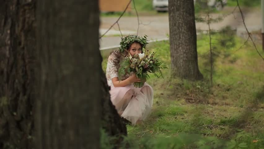 Cute girl with wreath her head hid behind tree