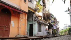 A young traveler woman runs the old city, by rail road and looks around. Vietnam, Hanoi city, Train street. Slow motion video