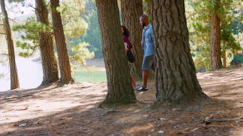 Couple On Countryside Hike Walking Through Woods By Lake