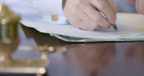 A closeup shot of Caucasian businessman wearing a dress shirt and cufflinks writing on a legal document with a fountain pen. 4k