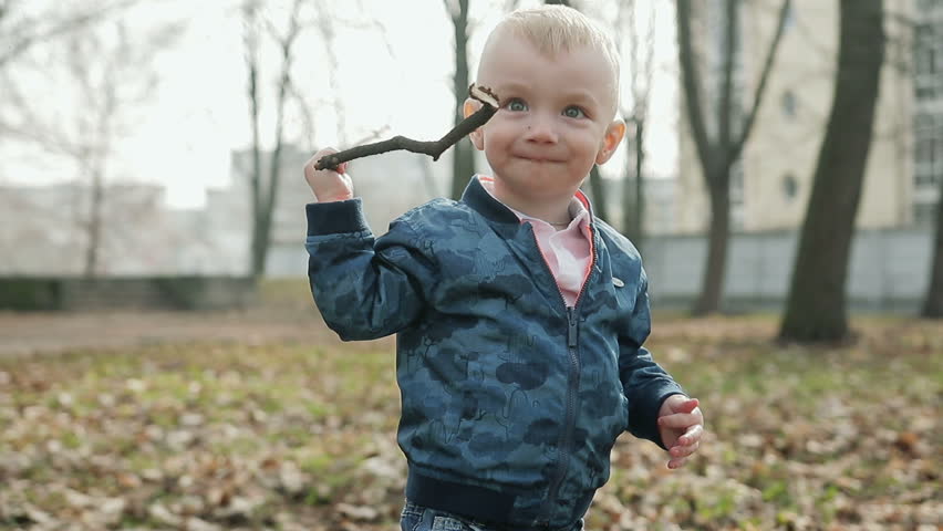 Funny little boy throws a branch on the ground. Steadicam shot