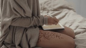 close up shot of woman hands, lady draws art objects on a portable tablet using a pencil, on her leg is a mandala made with henna, buta is a guardian - Powered by Shutterstock - Get 15% off with code: PIKWIZARD15