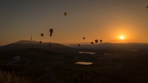 Silhouette time lapse of hot air balloons at sunrise flying over beautiful landscapes in Canberra, Australia.