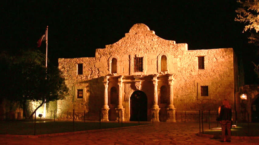 Video of front of the Alamo shrine in San Antonio Texas at night under lights. Texas flag. Historic famous building Texas independence battle with Mexico. 