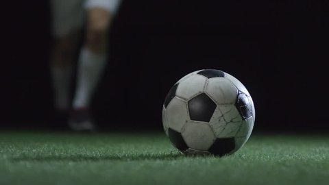 Closeup of soccer ball shoot by professional player on stadium field with artificial turf