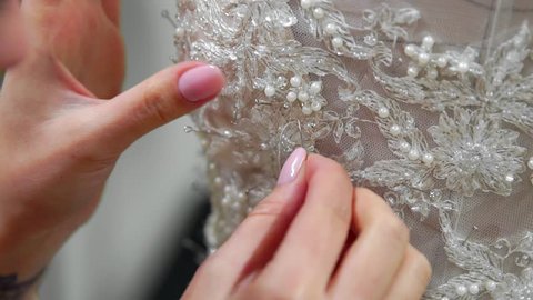 Close-up fashion designer for brides in his Studio pins needles lace wedding dress. Seamstress creates an exclusive wedding dress. Secure with pins and needles outline. Small private business.