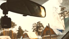 Driving car in winter countryside in slow motion. Sunset sun in rear view mirror
