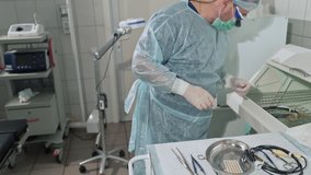 Funny video, a surgeon pulls out medical instruments from the sterilization apparatus and tosses a clamp in his hand. The doctor in professional outfits works in the hospital.