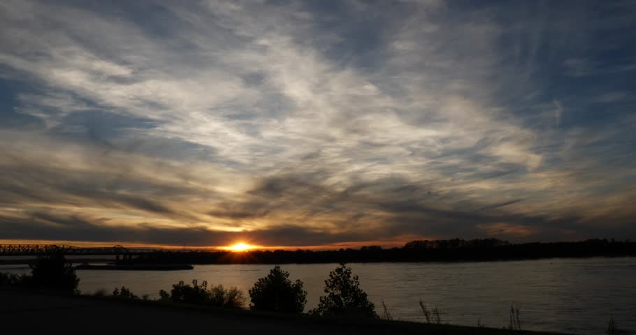 Colorful cloudscape over the Mississippi River at sunset with a cargo boat cruising by on the river Memphis Tennessee