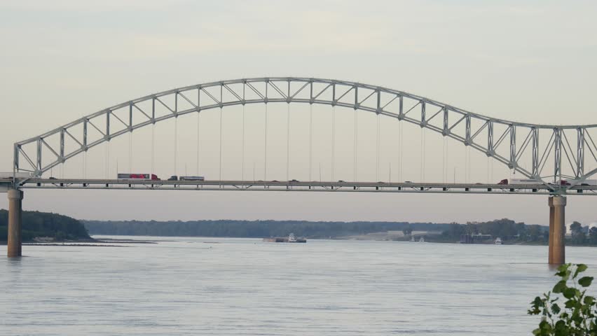 Traffic with freight trucks and motor vehicles crossing a bridge over the Mississippi River at Memphis Tennessee viewed from up river