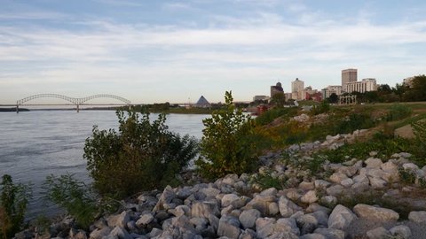 View along the bank of the Mississippi River to Memphis Tennessee on the skyline with rocks and vegetation in the foreground