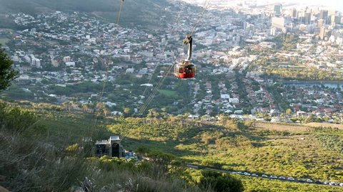 Cape Town Table mountain descending cable car approaching bottom station with city panoramic view below & green mountain slopes 