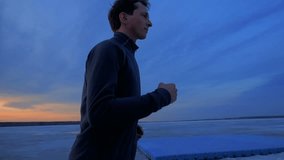 Young Man Training Outside In The Evening. Man exercising at sunset in city. Exercise and healthy lifestyle video.