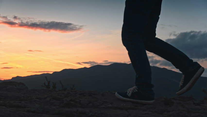 Closeup of male feet and stony path in sunset