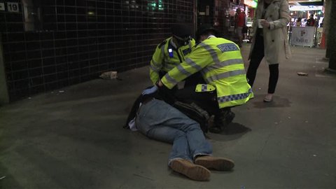 London, United Kingdom (UK) - 03 28 2012: Metropolitan police officers attend to a collapsed drunken man