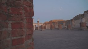 The moon on the sky in the archeological site in Pompeii Italy with the tall tower of ruined walls in the site