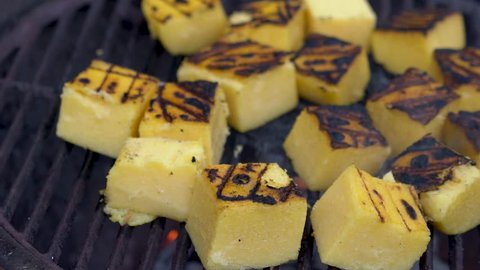 Closeup of polenta on a grill with smoke rising.
