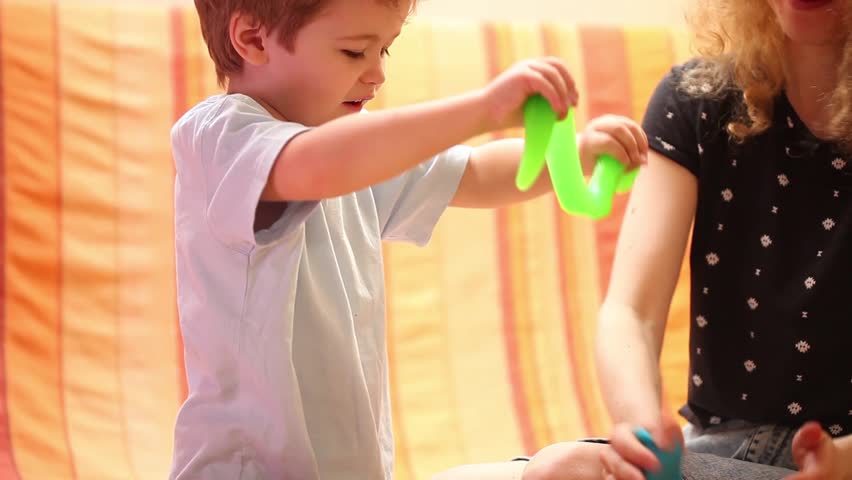 Funny game at home with mom. Cute child plays with green slime. A fun game for the development of sensations and dexterity. Enjoying the game. Joy mood. Happy childhood. Mother and son