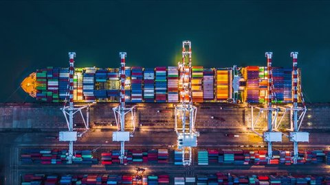 Container ship at deep sea port at night, Business import export logistic and transportation of International by container ship in the open sea, Aerial view time lapse, 4K