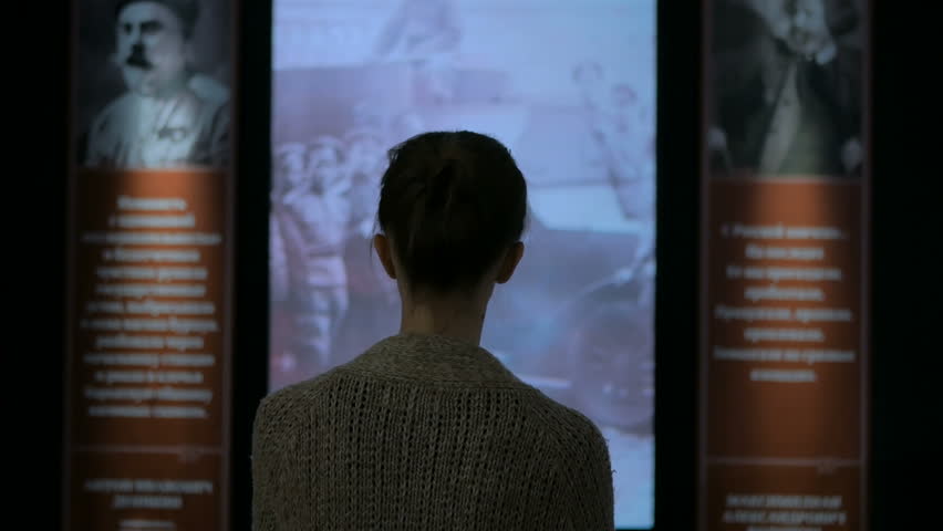 Young woman looking around in modern historical museum. Evening time, lowlight. Education and entertainment concept