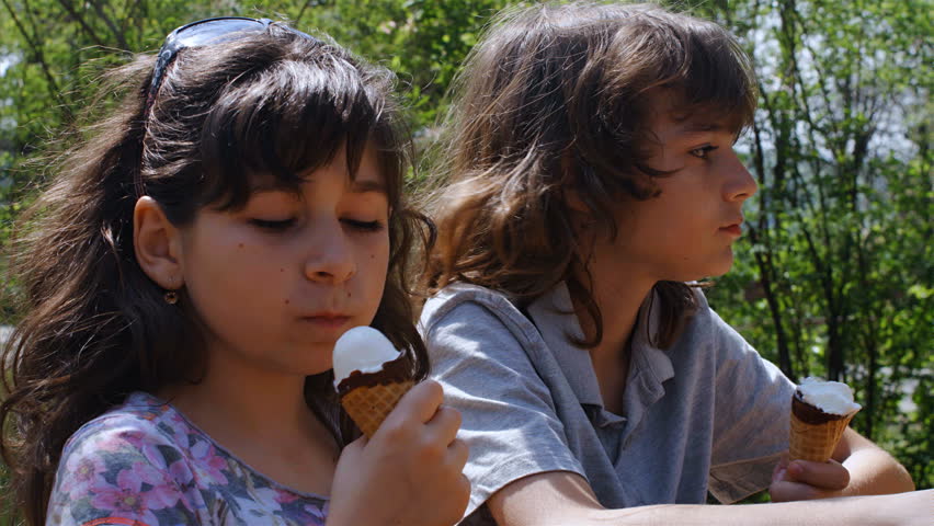 Boy and girl eating ice creams in the park, 4k