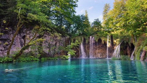 Prevalek Falls surrounded by tall trees are flowing into turquoise crystal clear waters on a sunny day / Plitvice Lakes National Park, Croatia. Shot with RED Weapon Helium 8K camera.