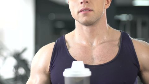 Bodybuilder drinking protein shake for muscle gain, sport bar, healthy diet