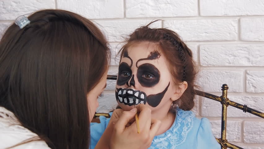 Makeup to the child. Draw on the face. Child on Halloween.