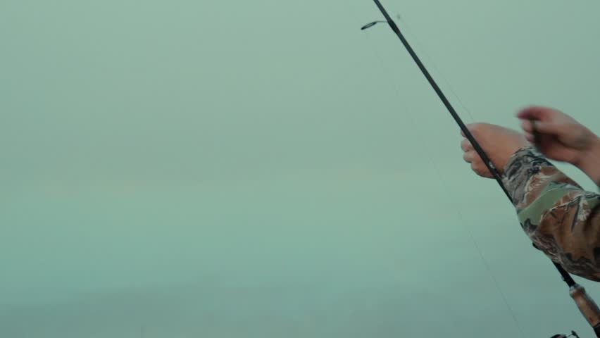 Guy with spinning Fisherman with spinning close-up on the bank of the lake on a foggy morning