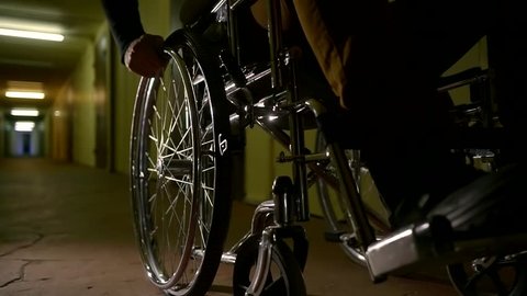 Close up shot of a disabled man on a wheelchair in abandoned scary hospital.