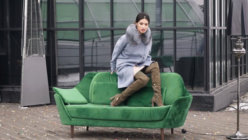 Street photo shoot of a girl in a coat. Photoshoot for the catalog of a coat. Portrait on a black background. Model posing on camera.