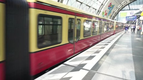 Berlin Hauptbahnhof, Germany, April 14 2018: S-Bahn train departing from Deutsche Bahn DB Main Railway Station platform, red wagons with commuters gaining speed, Berlin Central Station indoor view